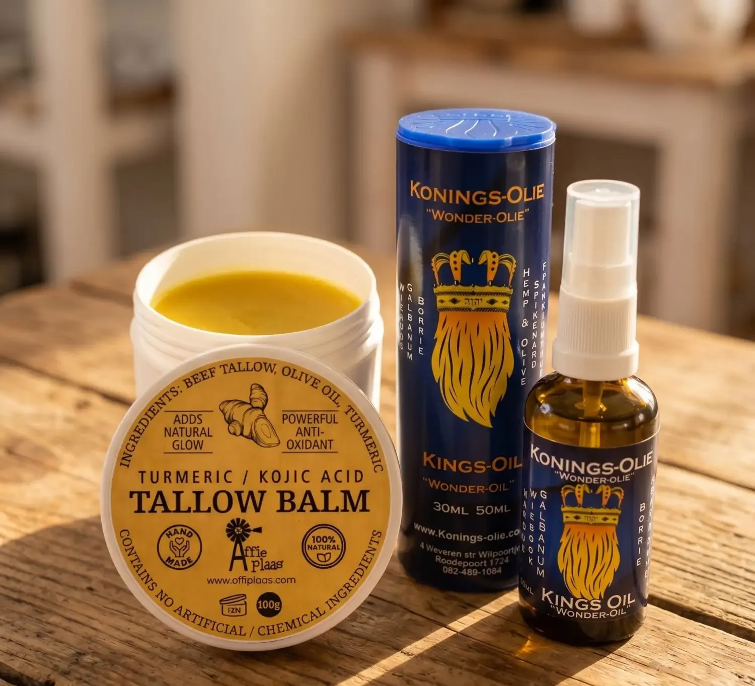 Affieplaas Turmeric Kojic Acid Tallow Balm open tub and Kings-Oil Wonder Oil spray bottle with tube packaging on a rustic wooden surface, showing South African natural skincare products containing turmeric